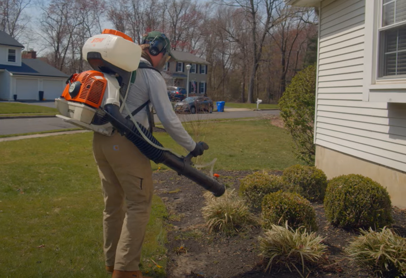 A technician using a backpack sprayer to treat the yard for mosquitoes and insects as part of a professional pest control service in Council Bluffs.