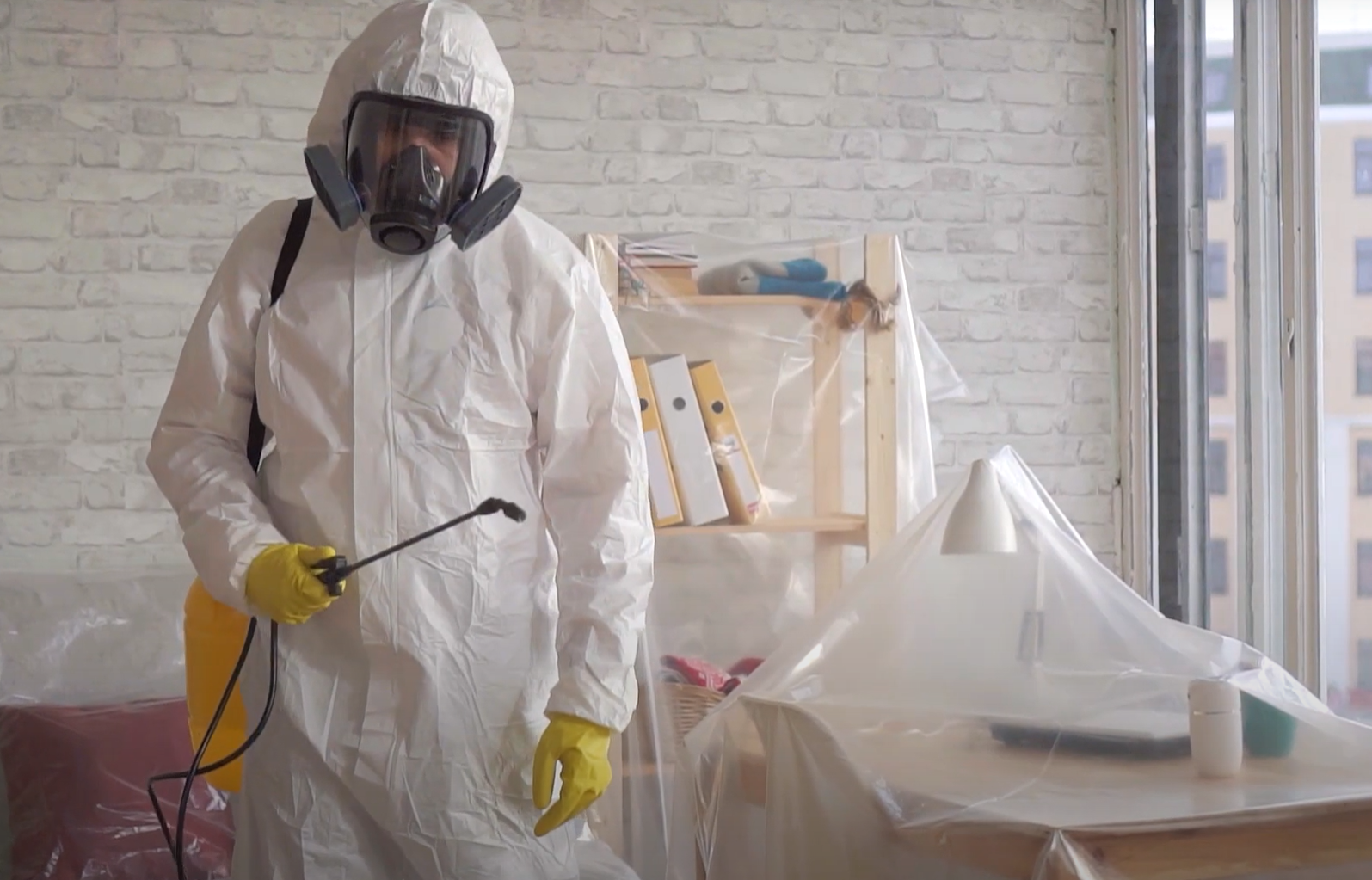A pest control expert in full protective gear spraying indoors as part of a thorough pest control service in Council Bluffs.